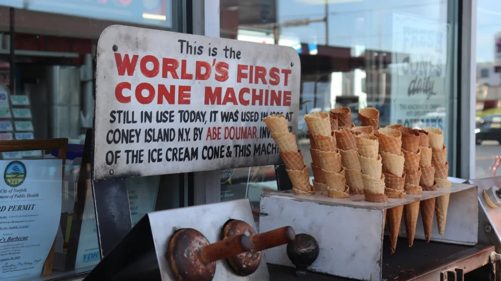 Stacks of empty ice cream cones and the irons used to shape them next to a sign stating This is the world's first come machine