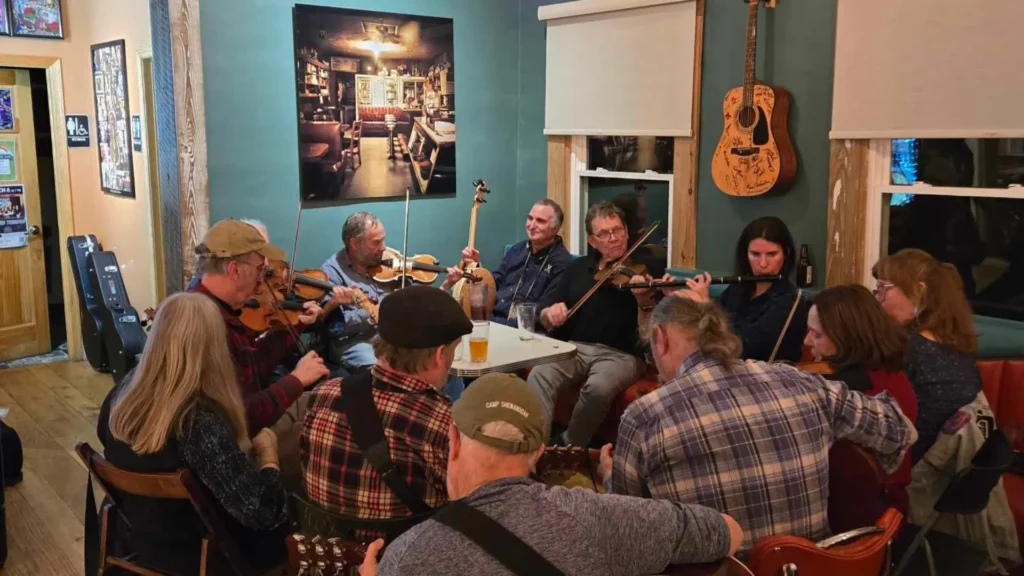 Group of musicians seated in a close circle playing music