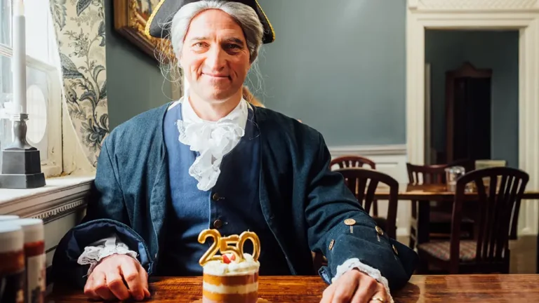 George Washington re-enactor enjoying a cake with candles in the shape of 250